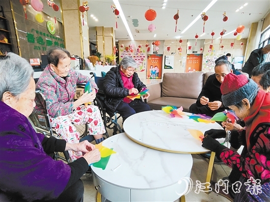 老人們圍坐在桌前，專注地制作小風(fēng)車。