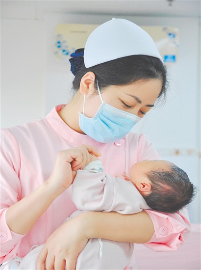 這是一雙托起生命的手。江門市中心醫(yī)院愛嬰?yún)^(qū)主管護(hù)師湯玲玲正在安撫哭鬧的寶寶。她一手環(huán)住襁褓，一手牽起寶寶的小手，動作舒緩而溫柔。在這里，生命的啼哭與溫柔的守護(hù)相遇，匯聚成世間至暖的力量。（林錦棠