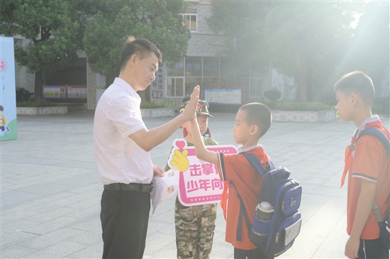 紫茶小學黨委書記譚國池與學生逐一擊掌。