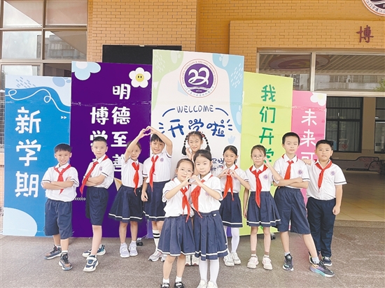 開學首日，農(nóng)林雙朗小學的學生們在學校精心準備的背景板前留影。