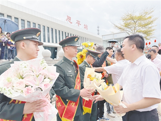 迎接隊(duì)伍工作人員為退役軍人佩戴“光榮返鄉(xiāng)”綬帶，送上鮮花。