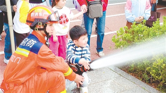 在消防員的指導下，小朋友體驗使用消防水槍。