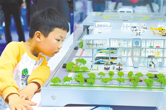 圖為當日，小朋友在第四屆科交會上觀看一款低空樞紐起降場模型。