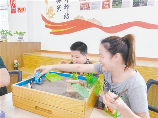 家長和孩子分別認(rèn)真挑選沙具，專注地搭建場景、勾勒畫面。