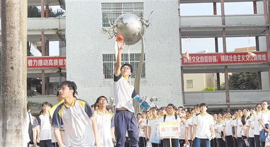 恩平市華僑中學校園廣場懸掛著3只“粽子”，路過的考生們紛紛踮腳跳躍，抬手觸碰“粽子”，取“高中”美意。梁曉敏